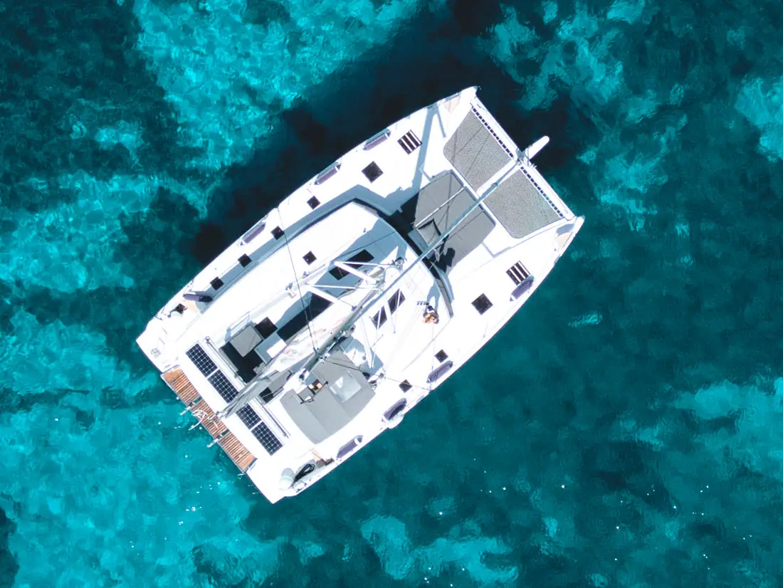 A catamaran at anchor over turquoise reef water